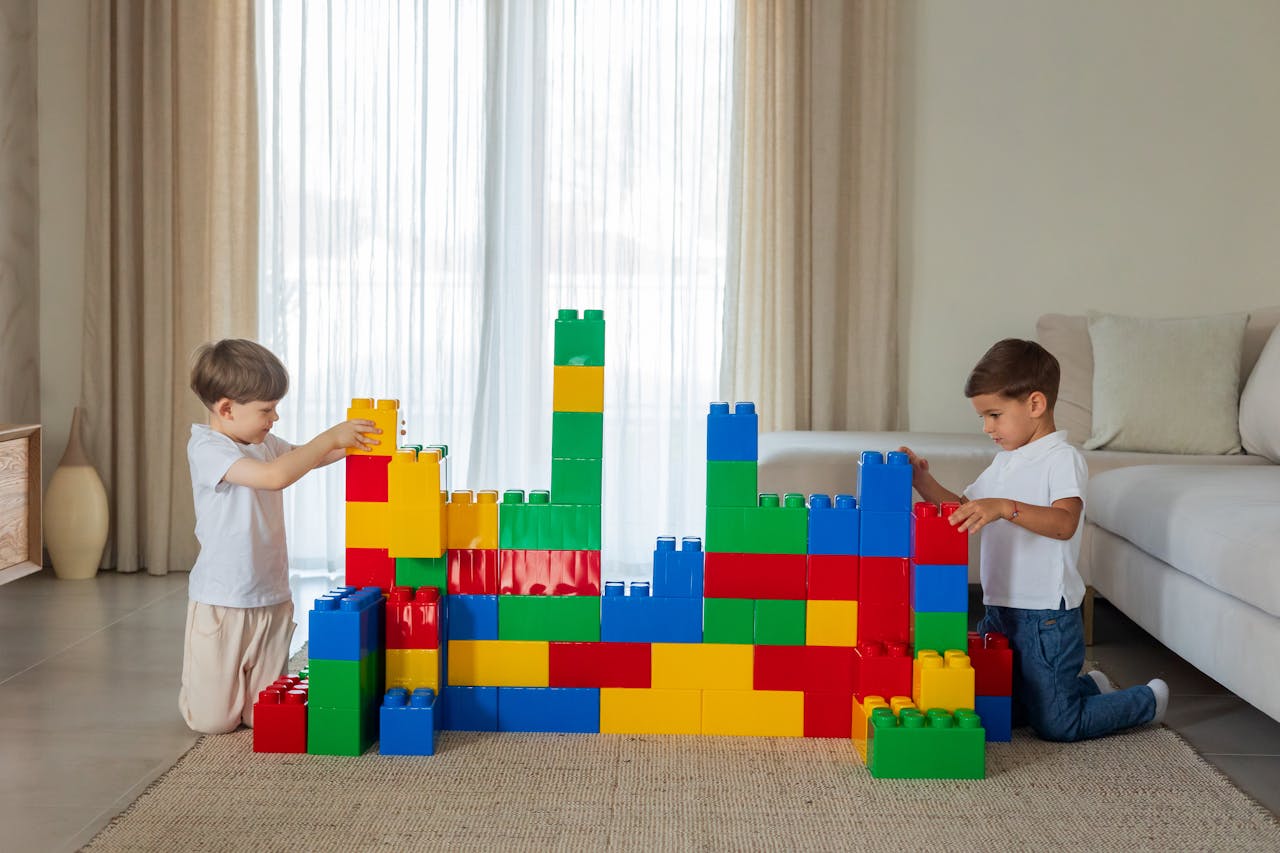 Two boys enjoy building with large colorful toy blocks in a cozy indoor setting.